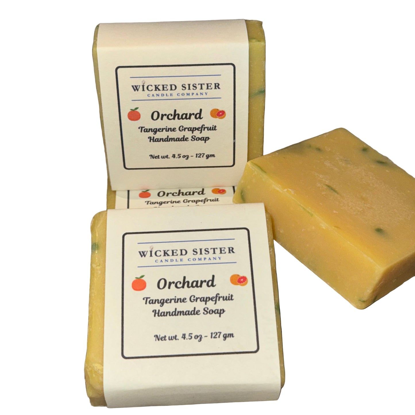 Two bars of 'Orchard Tangerine Grapefruit' handmade soap by Wicked Sister Candle Company on a white surface.