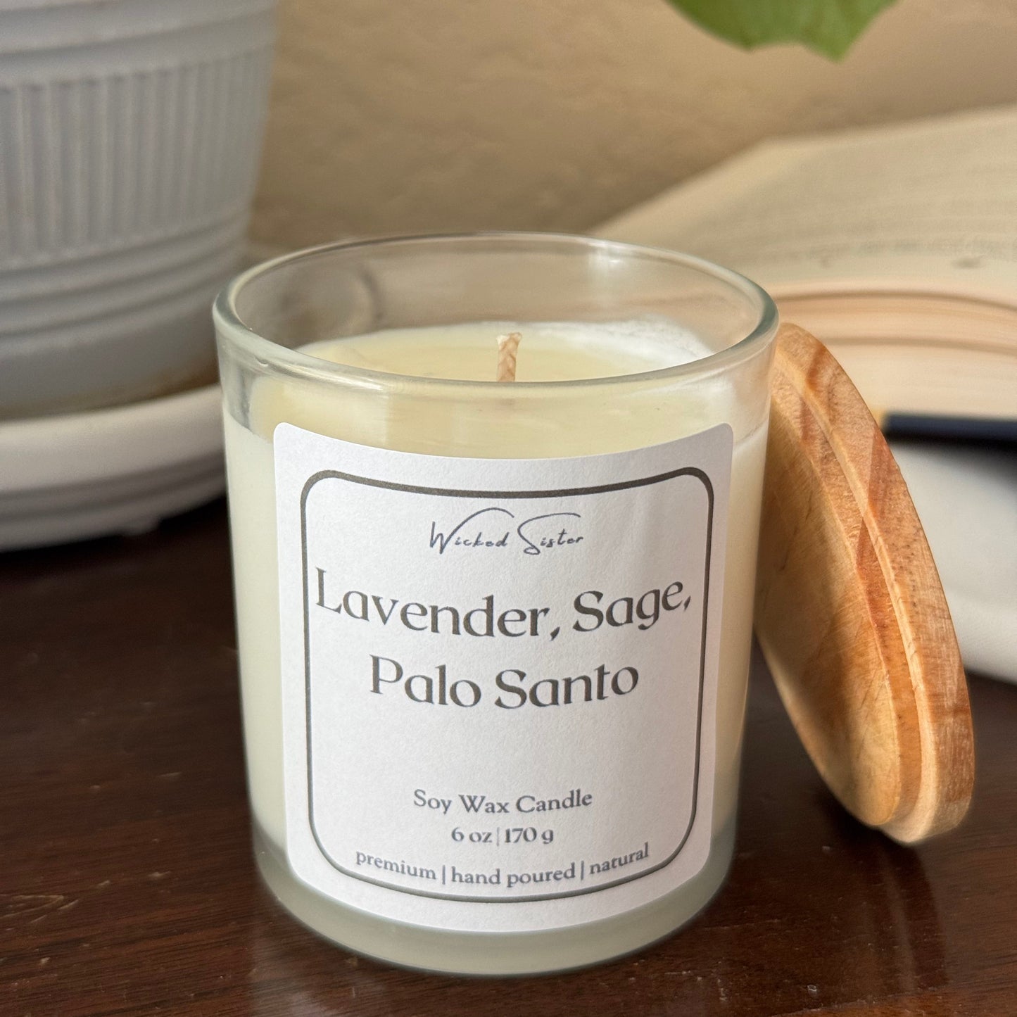 Lavender candle with a wooden lid on a surface with a leaf in the background
