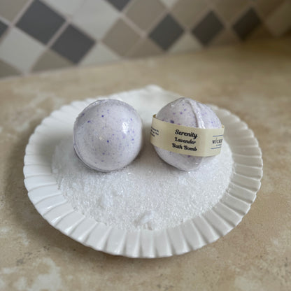 Two lavender bath bombs on a white seashell plate with a checkered tile background