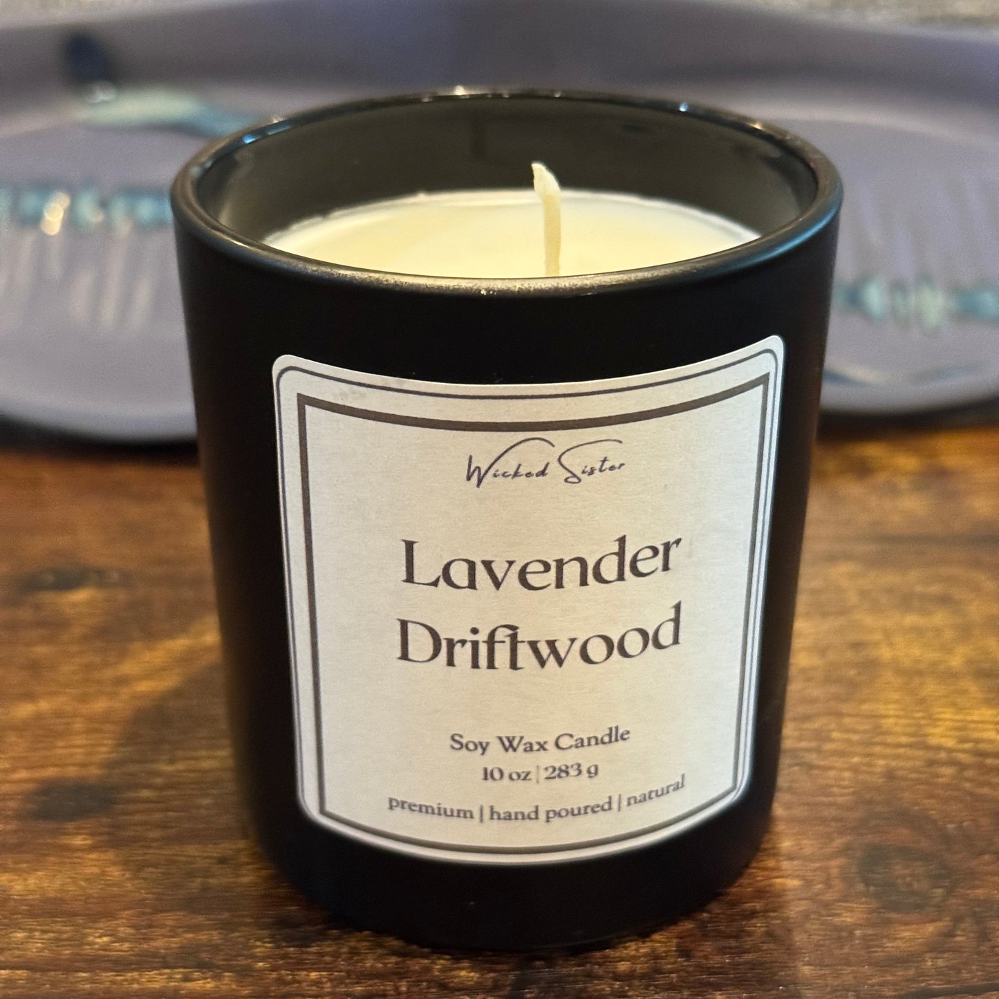 Black candle with 'Lavender Driftwood' label on a wooden table