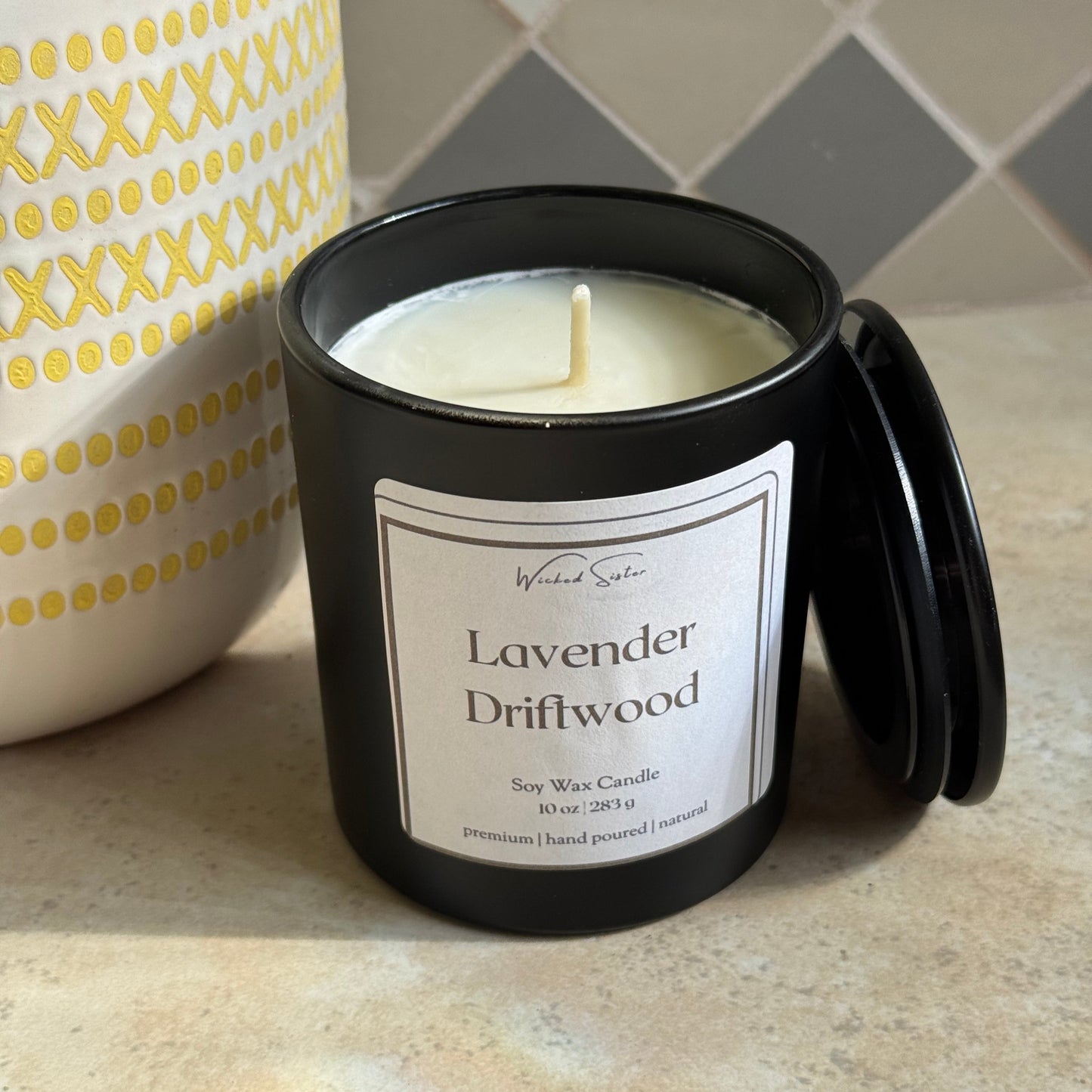 Black candle jar with a label on a marble surface