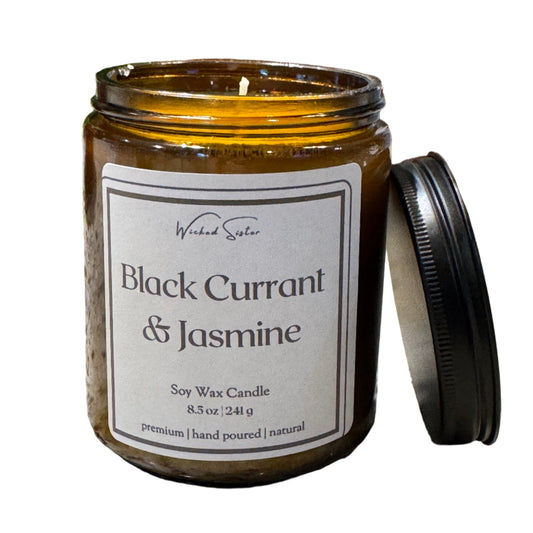 Candle jar labeled 'Black Currant & Jasmine' on a stone surface with a wooden lid.